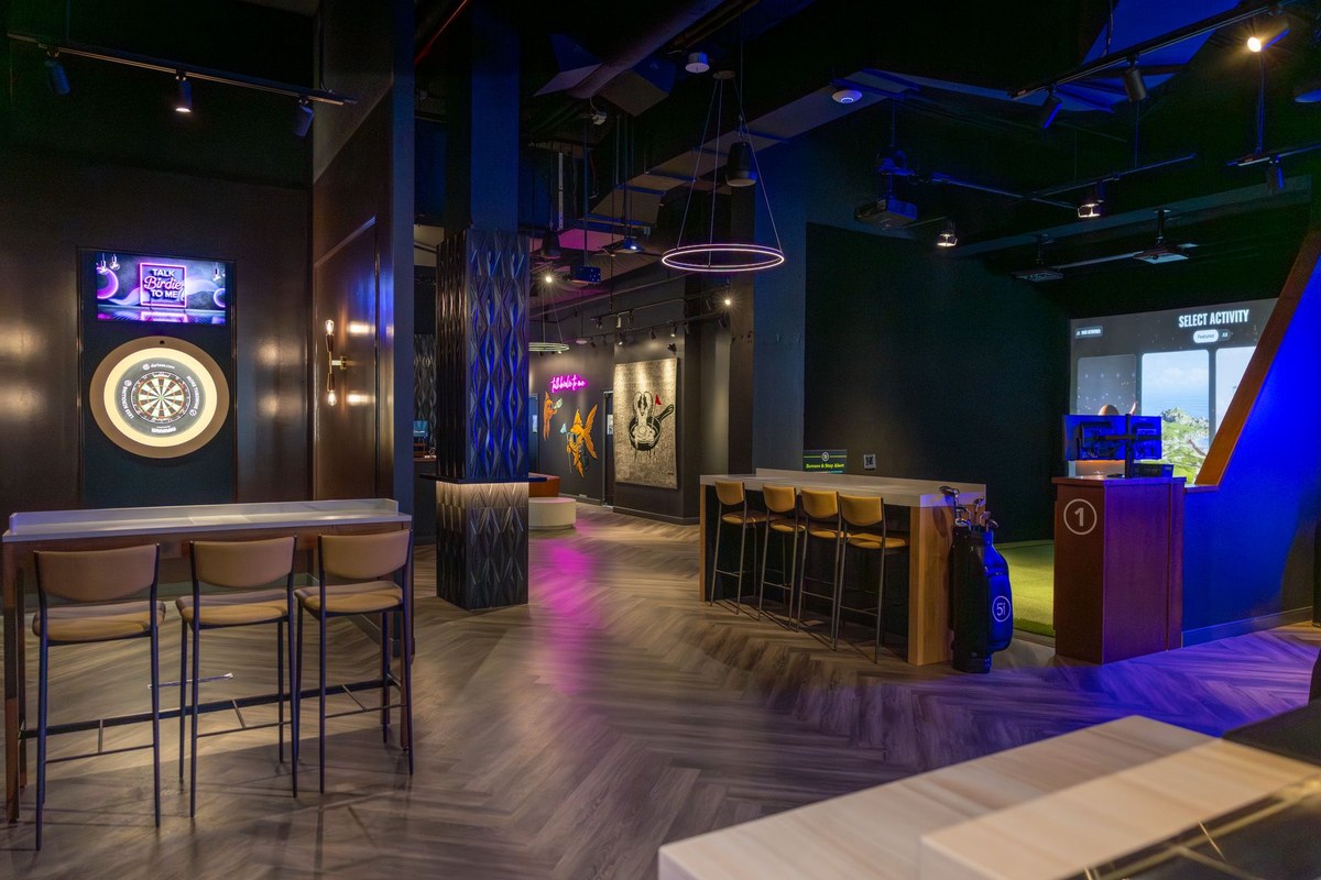 CORCON tenant improvement buildout for Five Iron Golf's Flatiron flagship in New York City — dartboard lounge and high-top bar seating alongside a simulator bay